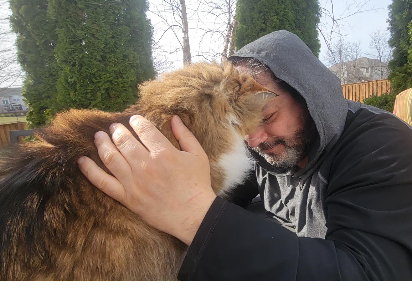 Dr. James and his cat pressing foreheads together in the backyard